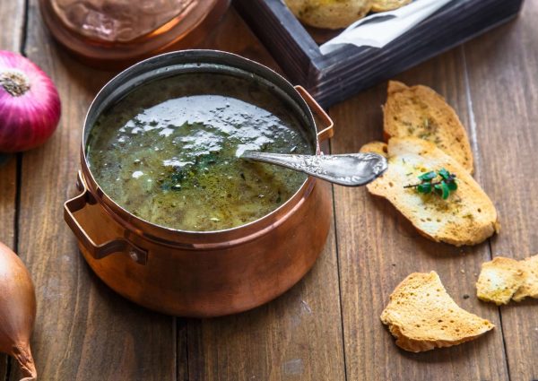 Close view of copper pot with onion soup and croutons